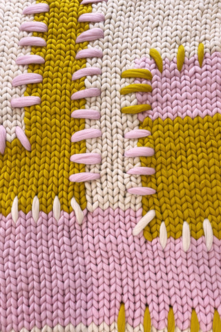 Handmade cream, pink and mustard colour block super chunky knitted blanket with thick patchwork stitching.
