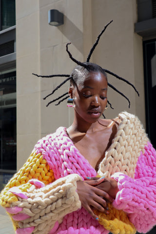Model wears handmade multicoloured colour block chunky knitted cardigan  in the streets of London