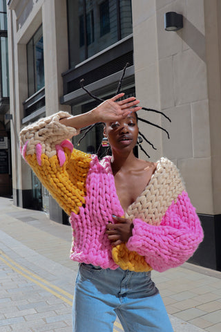 Model wears handmade multicoloured colour block chunky knitted cardigan  in the streets of London